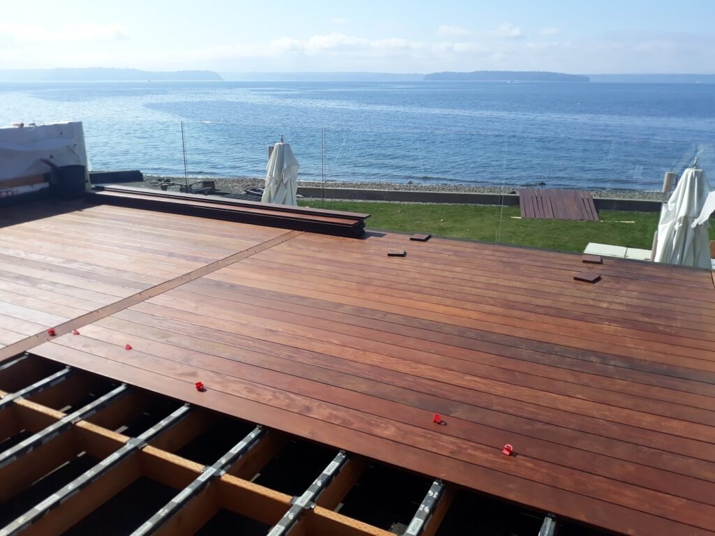 Ipe decking with oil finish applied on both sides. Glass panel railing facilitates a beautiful view of the ocean and a stunning clean deck surface thanks to the use of a hidden channel clip fastener system. Seaview Neighborhood, West Seattle