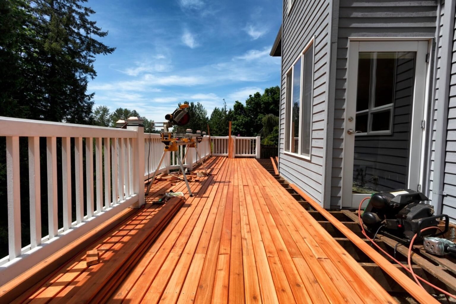 Capturing the process of modern deck construction, this image showcases a cedar deck in mid-installation. The bright cedar wood is laid out in a linear fashion, with tools on hand, illustrating the craftsmanship involved in creating a durable and attractive outdoor space